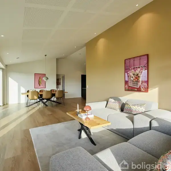 Grå sofa står i en moderne stue med træparketgulv. En moderne lampe lyser området op. Spisebord med stole ses i baggrunden, og store vinduer giver naturligt lys.