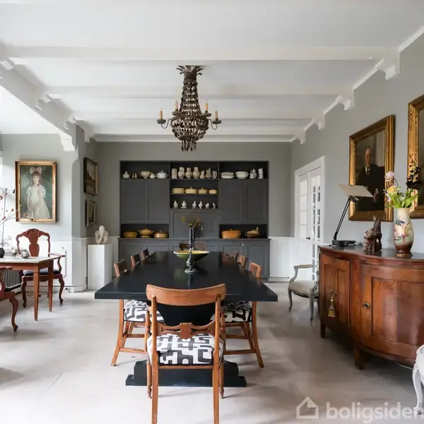 Et elegant spisestueinteriør med et langt, sort bord omgivet af træstole. Hylder med porcelæn og malerier på væggene omkranser rummet, som har grå vægge og paneler.