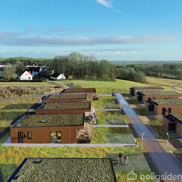 Flade, moderne huse med grønt på tagene ligger i to rækker. De er placeret på en græsbevokset grund med snoede stier, omgivet af åbent landskab og spredte træer.