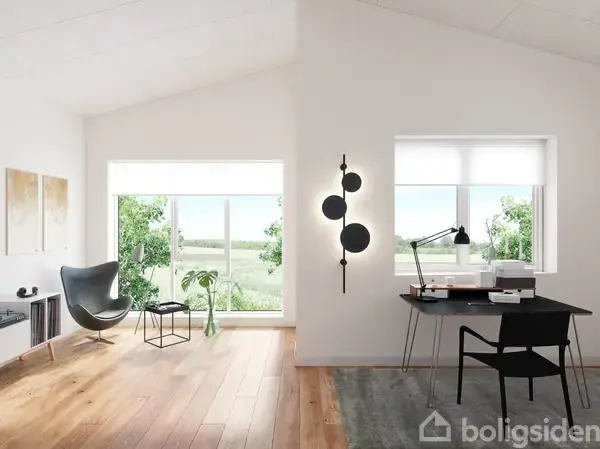 Et lyst rum med en lænestol til venstre ved store vinduer, en lille rund glasbord, og en skrivebord til højre med lampe og papirer under et vindue, omgivet af grøn natur udenfor.