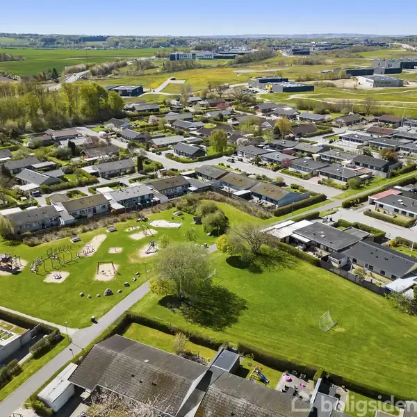 Bykvarter med lave, tætliggende huse. Grønne områder med legeplads og stier. Omgivet af åbne marker og skov. Husene har flade tage og små haver. Boligerne er adskilt af veje og gangstier.