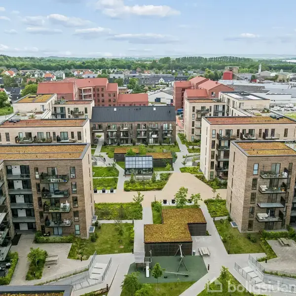 Flere lejlighedskomplekser omgiver en centralt placeret gård fyldt med grønne områder og legeplads, i en bymæssig bebyggelse. Bygningerne har flade tage og omfatter moderne arkitektur.