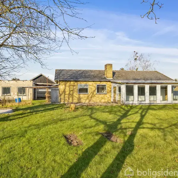 En gul murstensvilla med en glaseret udbygning står i en solrig have. Skygger fra træer falder på den velholdte græsplæne. Et klart, blåt himmelloft omgiver scenen.