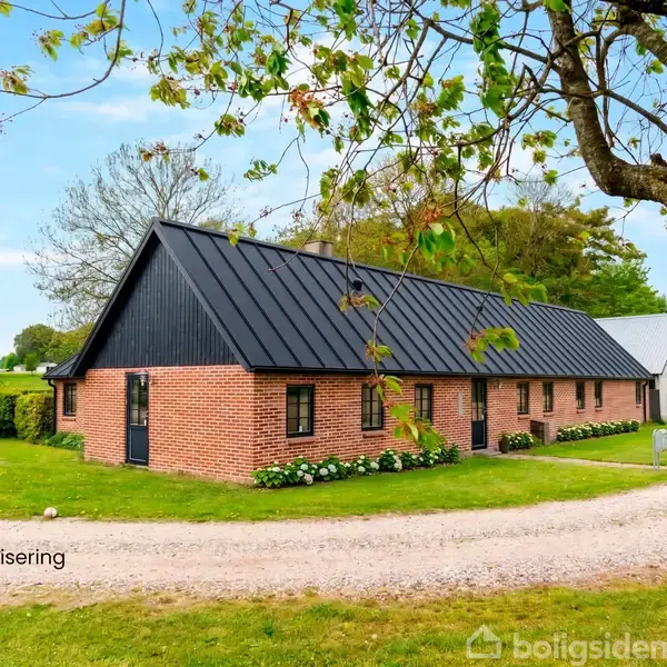 Rødt murstenshus med sort tag står stille på en grusvej omgivet af frodige træer og græs. Teksten "Visualisering" vises til venstre.