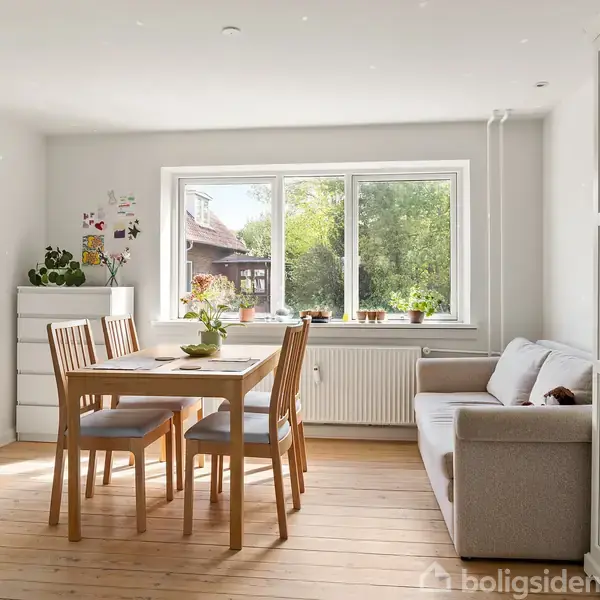 Et lyst rum med spisebord og stole centralt placeret. En sofa står ved siden af vinduet med udsigt til en grøn have. Et skab og en kommode omgiver området.