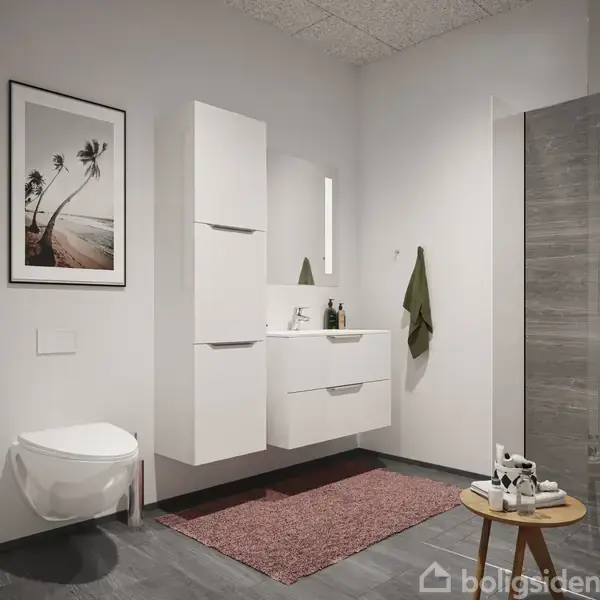 Hvidt badeværelsesskab med vask og spejl; omgivet af væghængt toilet, grøn håndklæde på krog og grå fliser i bruseniche. Vægdekoration med sort-hvidt palmestrandsfotografi til venstre.