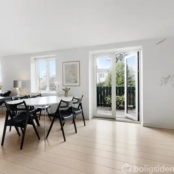 Spisebord med sorte stole står i en lys stue. Franske døre åbner ud til en balkon med grønne planter. Indbyggede hylder fyldt med bøger og dekorationer i venstre side.