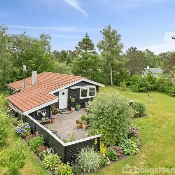 Hus med rødt tag står stille i en grøn have med farverige blomster og omkranset af træer. Tekst: "AI visualisering".