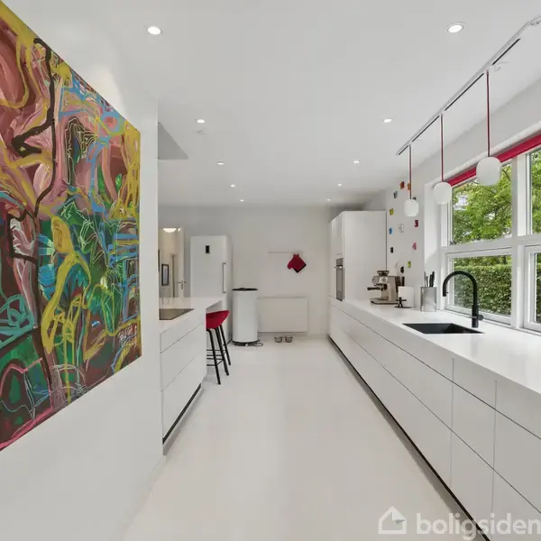 Et moderne køkken med hvide skabe og en sort vandhane ved en stor vindue. Et farverigt abstrakt maleri hænger på væggen. Grønne træer ses udenfor vinduet.