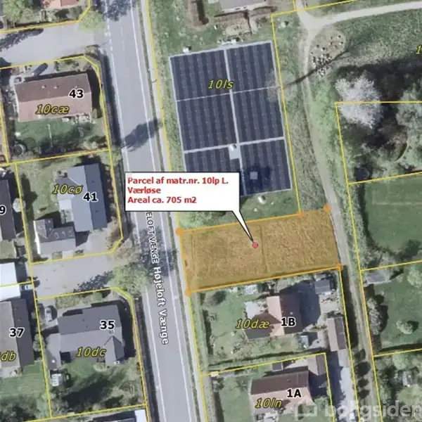 En matrikel afgrænset med gule linjer med teksten "Parcel af matr.nr. 10lp L, Værløse, Areal ca. 705 m2". Omgivet af bygninger, en vej og grønne områder.