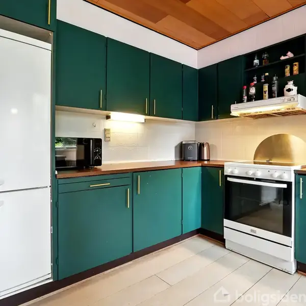 Et køkken med grønne skabe, en hvid ovn og køleskab. Der står en brødrister og mikroovn på bordpladen, mens en frugtskål er ved siden af.