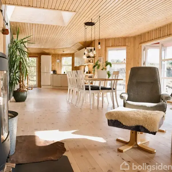 Græsareal strækker sig mod det bølgende hav, der møder en sandstrand under en overskyet himmel.