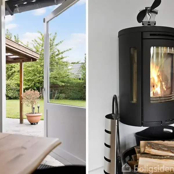 Brændeovn brænder ved siden af en kurv med brænde, flankeret af flasker. I baggrunden ses en overdækket terrasse med åben dør mod have.