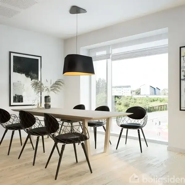 Bord omgivet af seks sorte stole står i en moderne, lys spisestue med kunst på væggene. Store vinduer giver udsigt til natur. En sort lampe hænger over bordet.