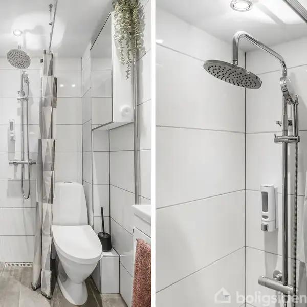 Brusekabine med regnbruser står i et hvidt flisebelagt badeværelse. Ved siden af hænger et bruseforhæng. Toilet og håndklæde er synlige på venstre side.