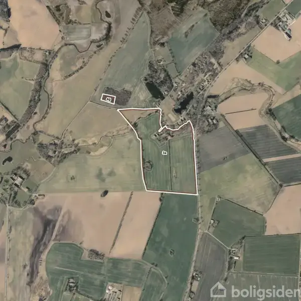 Luftfoto af landbrugsområde med marker afgrænset af hvide linjer. Området er omgivet af forskellige landbrugsejendomme, skove og marker i et varieret landskab.