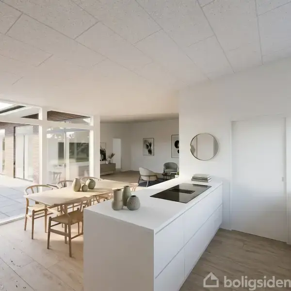 Et moderne køkken med hvidt interiør og en kogeø med kogezone, omgivet af et spisebord med stole. Store vinduer og en åben dør fører ud til en terrasse.