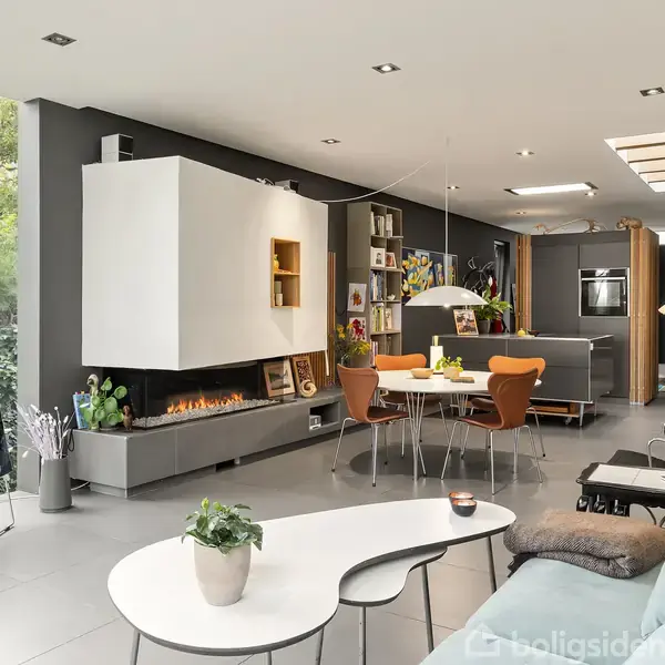 Et moderne opholdsrum med en lysegrøn sofa centreret mod en abstrakt farverig maleri. Foran sofaen står et hvidt, buet sofabord med en plante og en kogle.