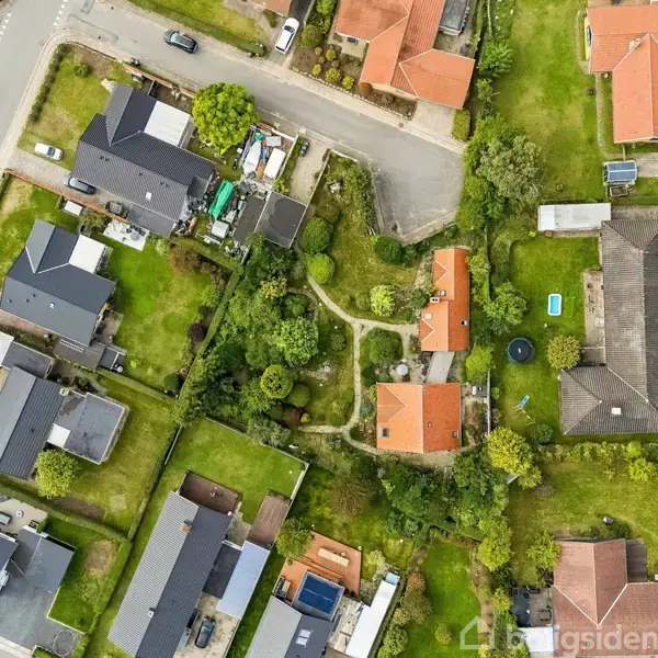 Huse med røde tage ligger i en række omgivet af grønne haver og veje. Billedet er taget fra oven, og det viser en velordnet boligblok.