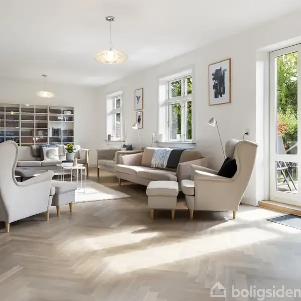 Et lyst, moderne stueinteriør indeholder en sofa, lænestol og sofabord. Værelset er fyldt med naturligt lys fra vinduerne, der åbner op til en grøn have udenfor. Indretningen er minimalistisk og hyggelig.