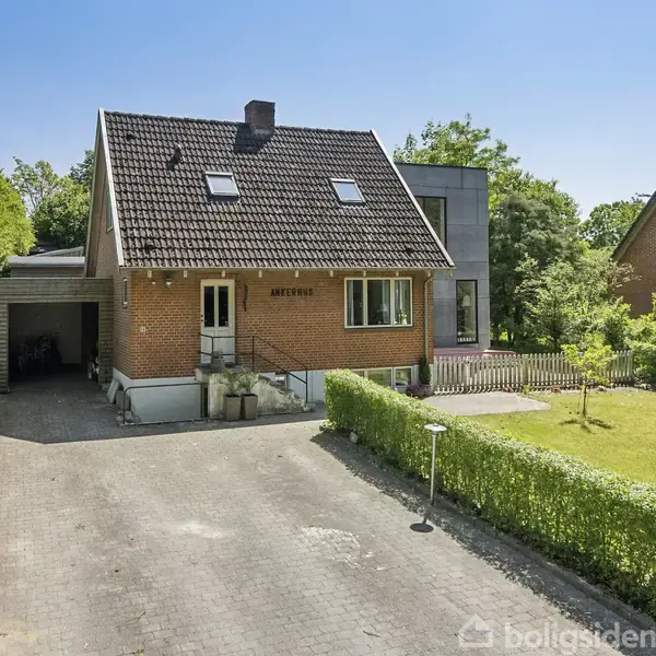 Huset er en rød murstensvilla med gavl og skråtag. Foran huset er der en stor indkørsel omgivet af hække. Tekst på huset: "ANEMONE".