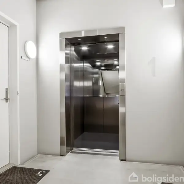 Elevator med åbne døre, belyst af loftslamper, i en lys gang med to lukkede døre til venstre og højre; væggen har et tal "1".