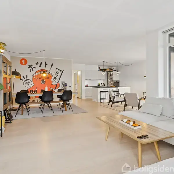 En moderne stue viser en sofa og et sofabord i forgrunden. Vægmaleri af en orange blæksprutte er bag spisebordet med stole. Køkkenet er synligt i baggrunden.