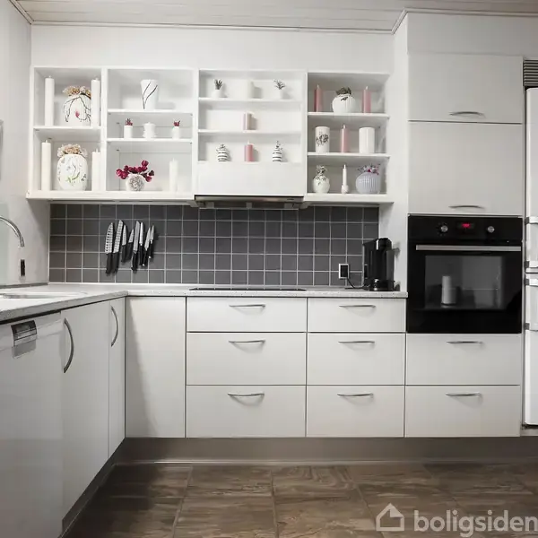 Køkken med hvide skabe, hylder med porcelænsfigurer, indbygget ovn, køleskab og opvaskemaskine. Knive hænger over en grå flisevæg. En plante og en kaffemaskine står på bordpladen.