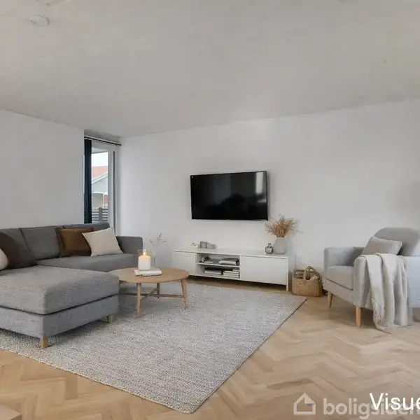 Grå sofa står i en lys stue med trægulv, placeret ved siden af et rundt sofabord med et tændt lys. En fladskærm hænger på væggen, omgivet af planter. Tekst: "Visuelt forslag".