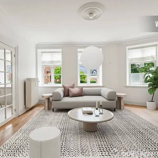 En lys stue med en sofa placeret mod bagvæggen, en rund bord i midten og en fladskærm på højre væg. Store vinduer giver udsigt til et grønt område. Tekst: "VISUALISERING".