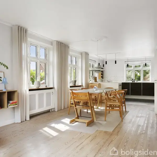 Et lyst køkken-alrum med spisebord og stole i træ. Store vinduer lader lys strømme ind. Køkkenet har mørke skabe, og en pejs i hjørnet giver hygge.