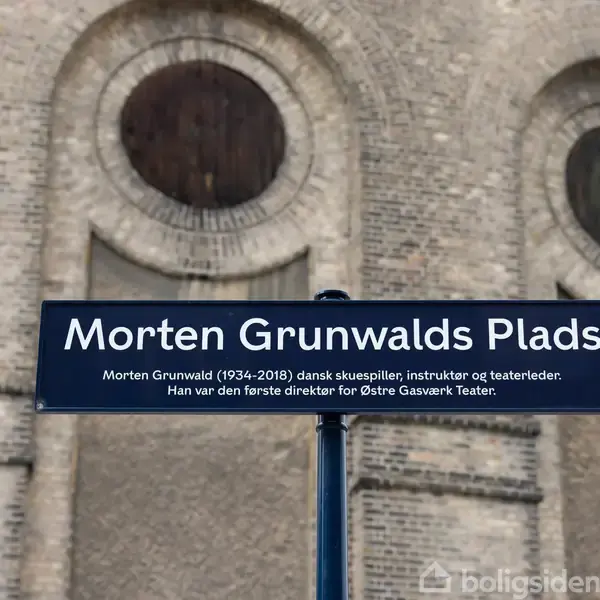 Et skilt står foran en murstensbygning, hvor der står: "Morten Grunwalds Plads. Morten Grunwald (1934-2018) dansk skuespiller, instruktør og teaterleder. Han var den første direktør for Østre Gasværk Teater."