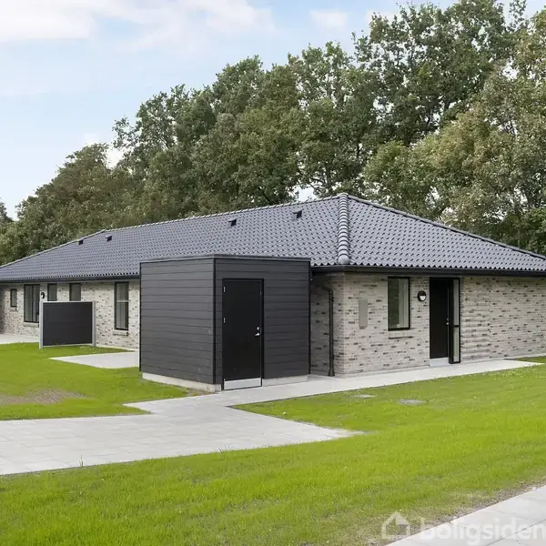 En moderne enfamiliehus i mursten står på en græsplæne, flankeret af en flisebelagt sti. Huset har et sort tag og sorte døre. Omkranset af træer.