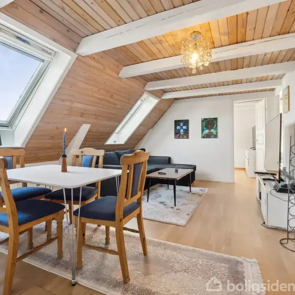 En rødstensbygning med trappe på ydersiden fører til tagetagen. Huset har hvide vinduer og en hoveddør med terrasse. Græsplæne og blomster omkranser huset i et solrigt område.