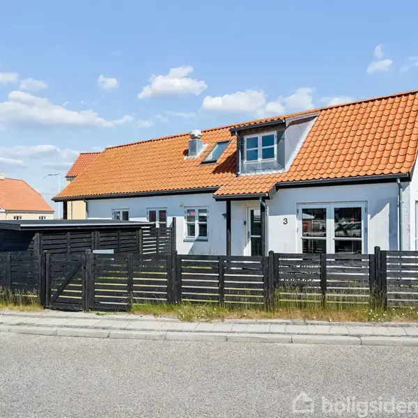 Hus med hvid facade og rødt tegltag, står bag sort trægærde. Gaden er tom, og himlen er blå med få skyer. Nummer 3 ses på facaden.