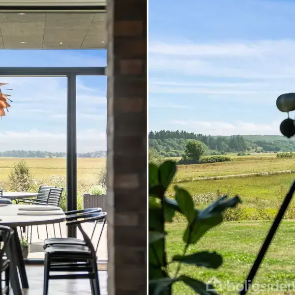 En spisestue med et rundt bord og stole vender mod en stor glasdør, der åbner ud til en terrasse med udsigt over en grøn mark og skov i det fjerne.