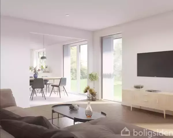 Stue med sofa og sofabord, hvor en vase står på bordet. TV på væggen. I baggrunden ses spisebord og stole ved store vinduer med udsigt til have.