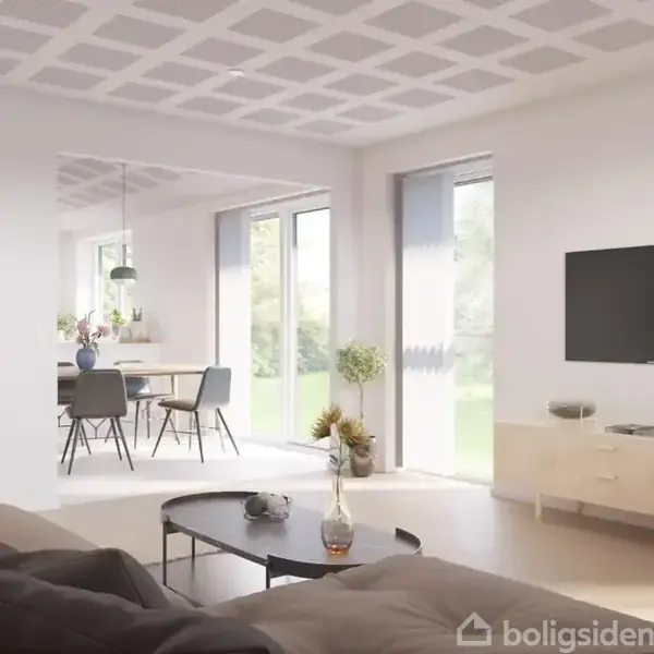En stue med sofa og bord foran et TV på væggen. Ved siden af er et spisebord med stole i et lyst rum med store vinduer.