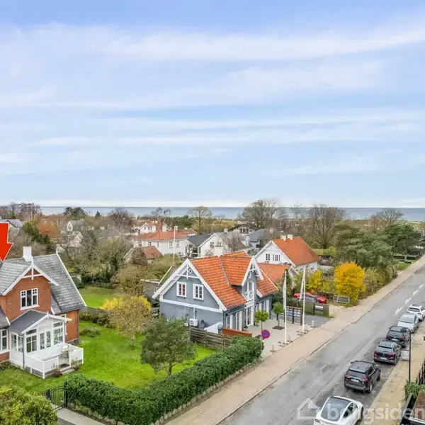 Vejen strækker sig fremad og er omgivet af grønne træer på begge sider under en blå himmel. Der er vejtavler og lygtepæle langs fortovet.