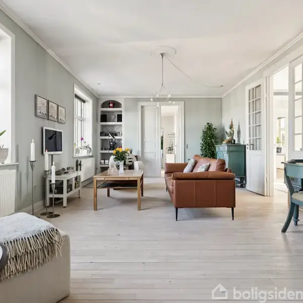 Stue med brunt sofabord og sofa, placeret i et lyst rum med store vinduer. Reoler, et tv og dekorativt inventar skaber en hyggelig atmosfære. Bord med grønne stole i baggrunden.