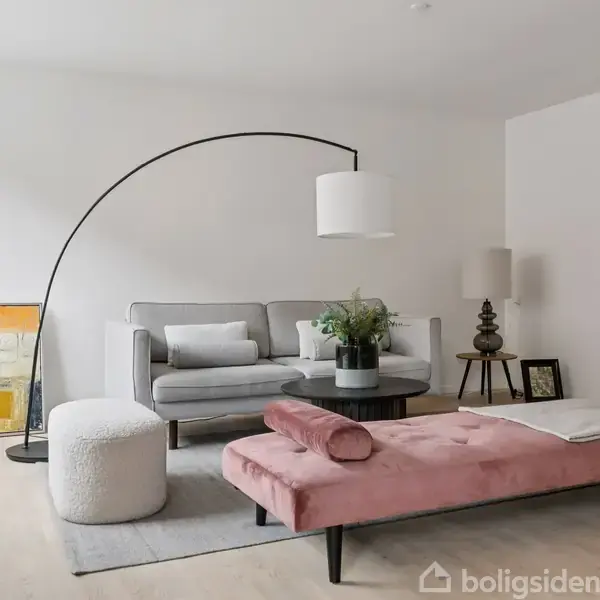 Gråt sofaarrangement med en moderne gulvlampedesign, omgivet af malerier og planter, i en lys stue med træmøbler og minimalistisk indretning.