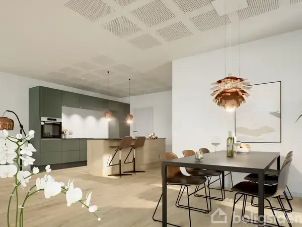 Et moderne køkken-alrum viser en rummelig køkkenø med barstole og hængende lamper over. I forgrunden står et spisebord med matchende stole. Rummet er lyst med minimalistisk indretning.