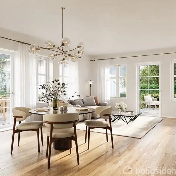 En lys stue indeholder et bord med stole og en moderne lysekrone, sofaområde i baggrunden. Store vinduer og døre åbner mod en terrasse, omgivet af grønne planter.