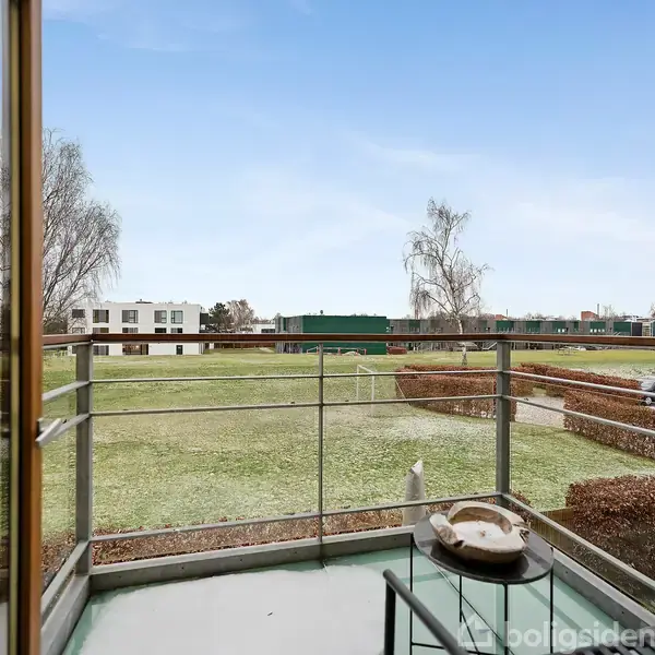 Et moderne køkken med hvide skabe og en træbordplade. En ovn og kogeplade er integreret. Køkkenet er oplyst med indbygget belysning, og planter pynter ved siden af vasken.