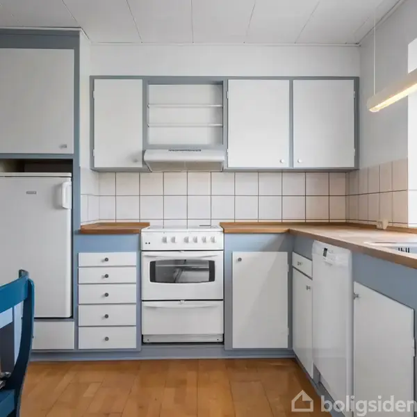 Et køkken med hvide skabe og træbordplader, indeholder komfur og vask. Et vindue på højre side giver udsigt til grønne omgivelser. En blå stol står ved et bord.