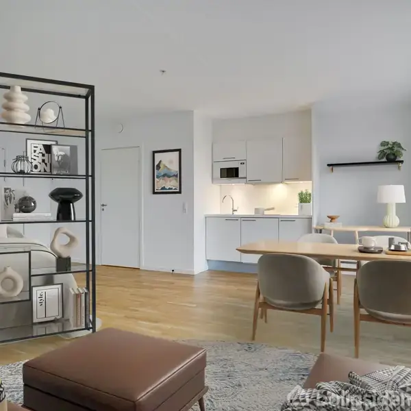 Reol med dekorative genstande står mod venstre i en moderne stue-køkken-alrum. Spisebord og stole til højre, køkken i baggrunden. Neutral farvepalet i indretning.