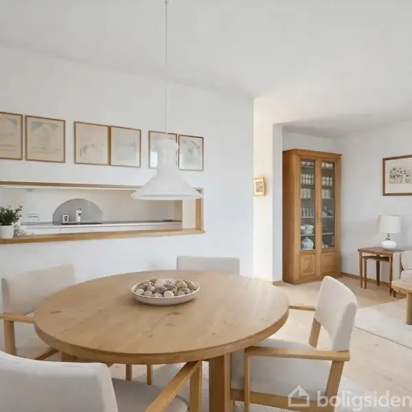 Rundt spisebord med skål fyldt med sten, står centralt i en lys stue. I baggrunden er en reol, sofa, bordlampe og billeder på væggene.