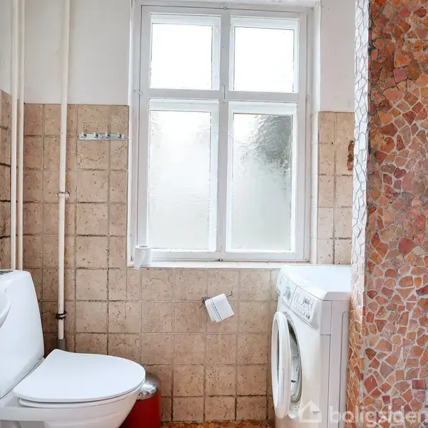 Toilet og vaskemaskine står side om side i et lyst badeværelse med flisebelagte vægge. Et vindue med frostet glas slipper lys ind i rummet.