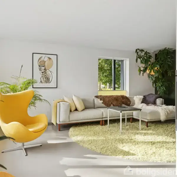 En gul lænestol står i stuen, solbeskinnet nær grønne planter. Ved siden af er en stor, lys sofa. Vinduet og vægkunst tilføjer moderne indretning. En brændende pejs opvarmer rummet.