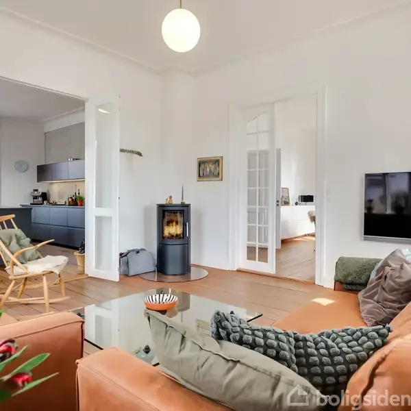 En rødstensvilla med skråtag og hvide vinduer står roligt. Trappen fører op til hoveddøren. Villaen er omgivet af en velholdt have og en nærliggende vej. Tekst: "VILLA TRESCHOW".